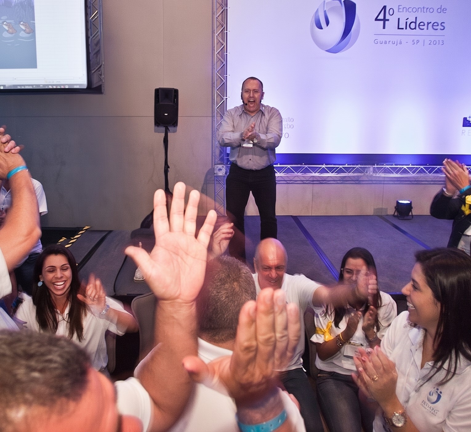 Rogério Chelucci no palco conduzindo dinâmica com plateia engajada
